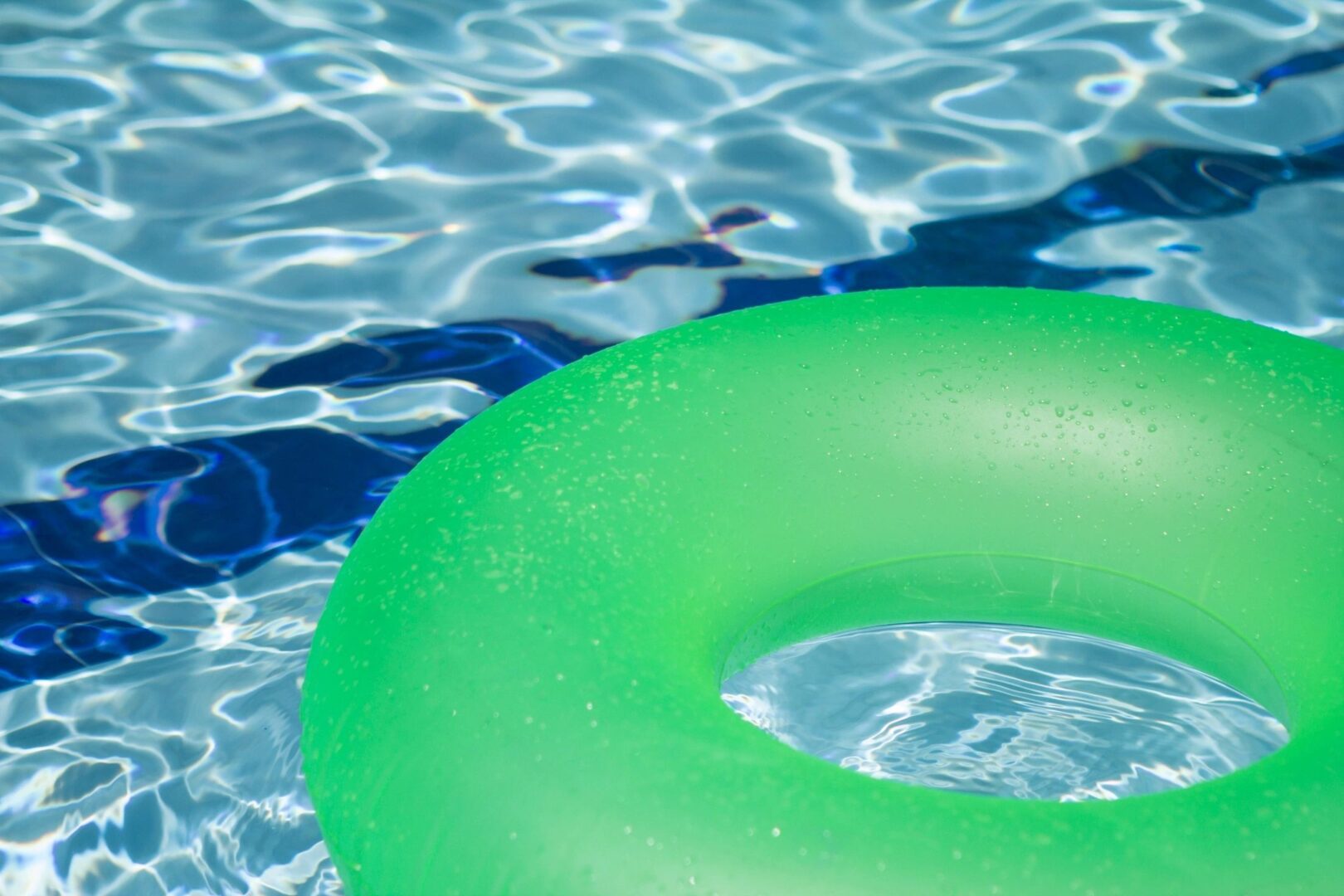 A green inflatable ring floating in a pool.